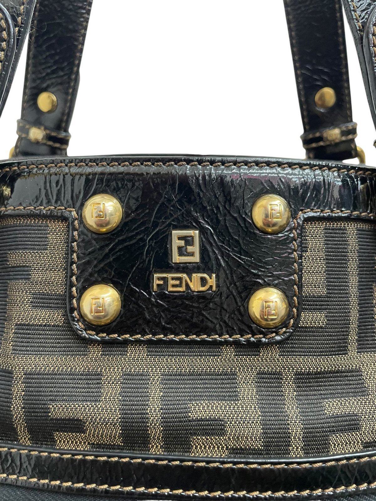 Dettaglio logo Fendi in metallo dorato lucido su borsa Zucca