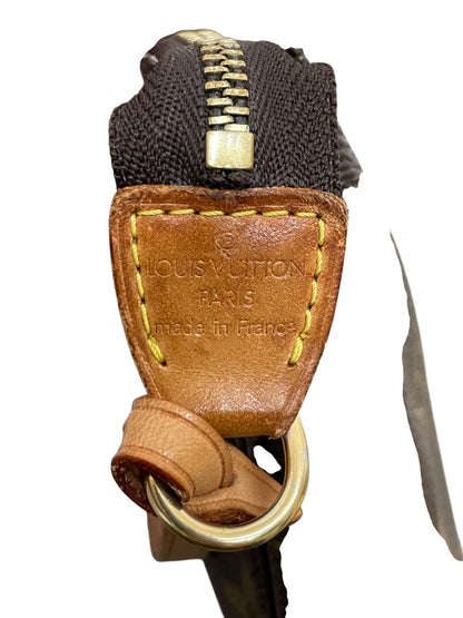 Primo piano della linguetta laterale in vacchetta con anello metallico della borsa Louis Vuitton Pochette Accessoires che mostra le cuciture gialle