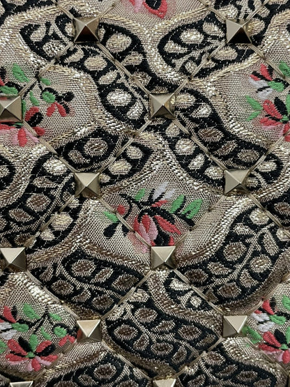 Dettaglio ravvicinato della trama del tessuto jacquard Papier Floral multicolor con ricami floreali rosa e verdi e micro-borchie piramidali applicate