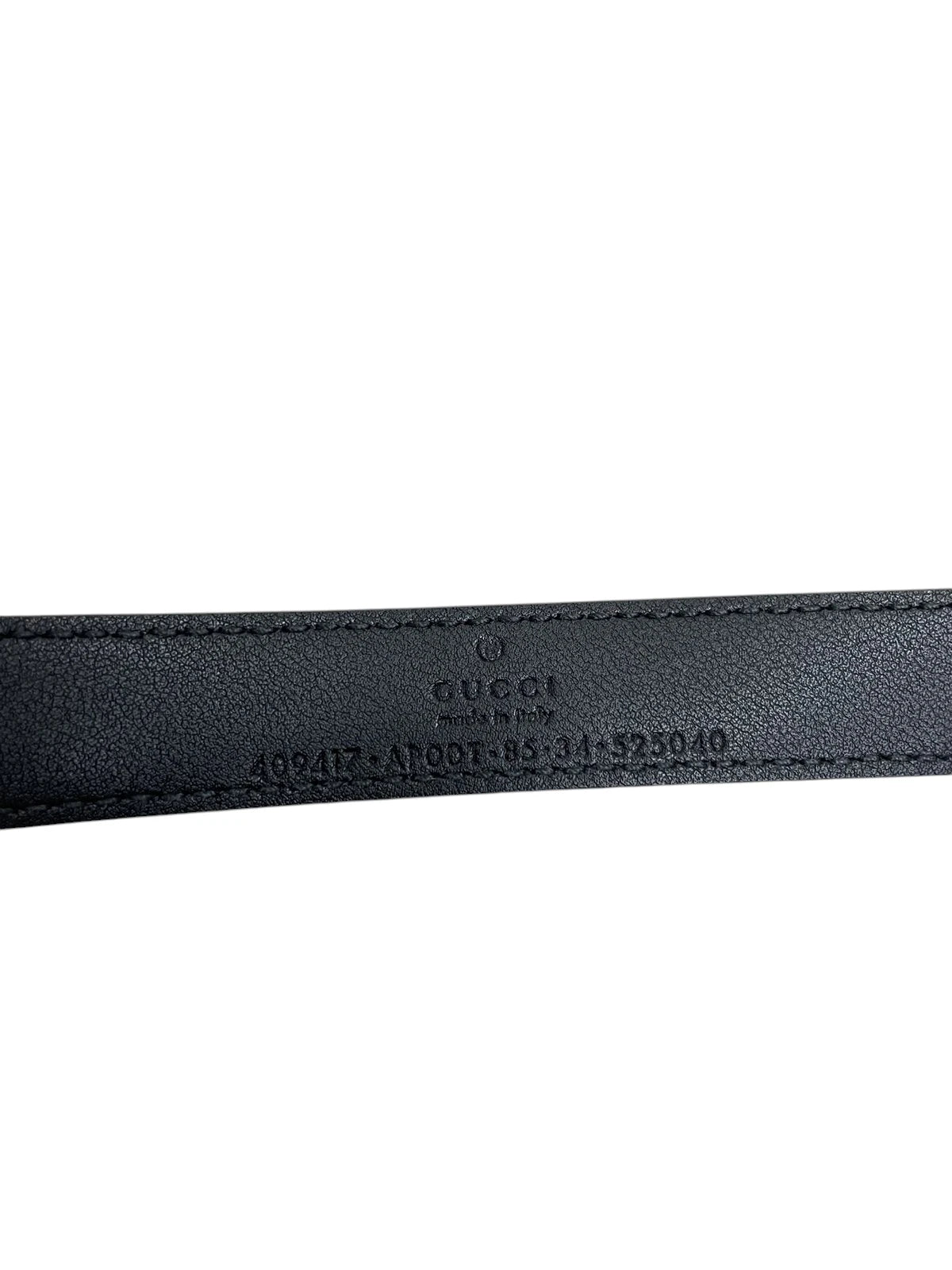 Dettaglio ravvicinato della trama e delle cuciture della pelle nera della cintura Gucci.