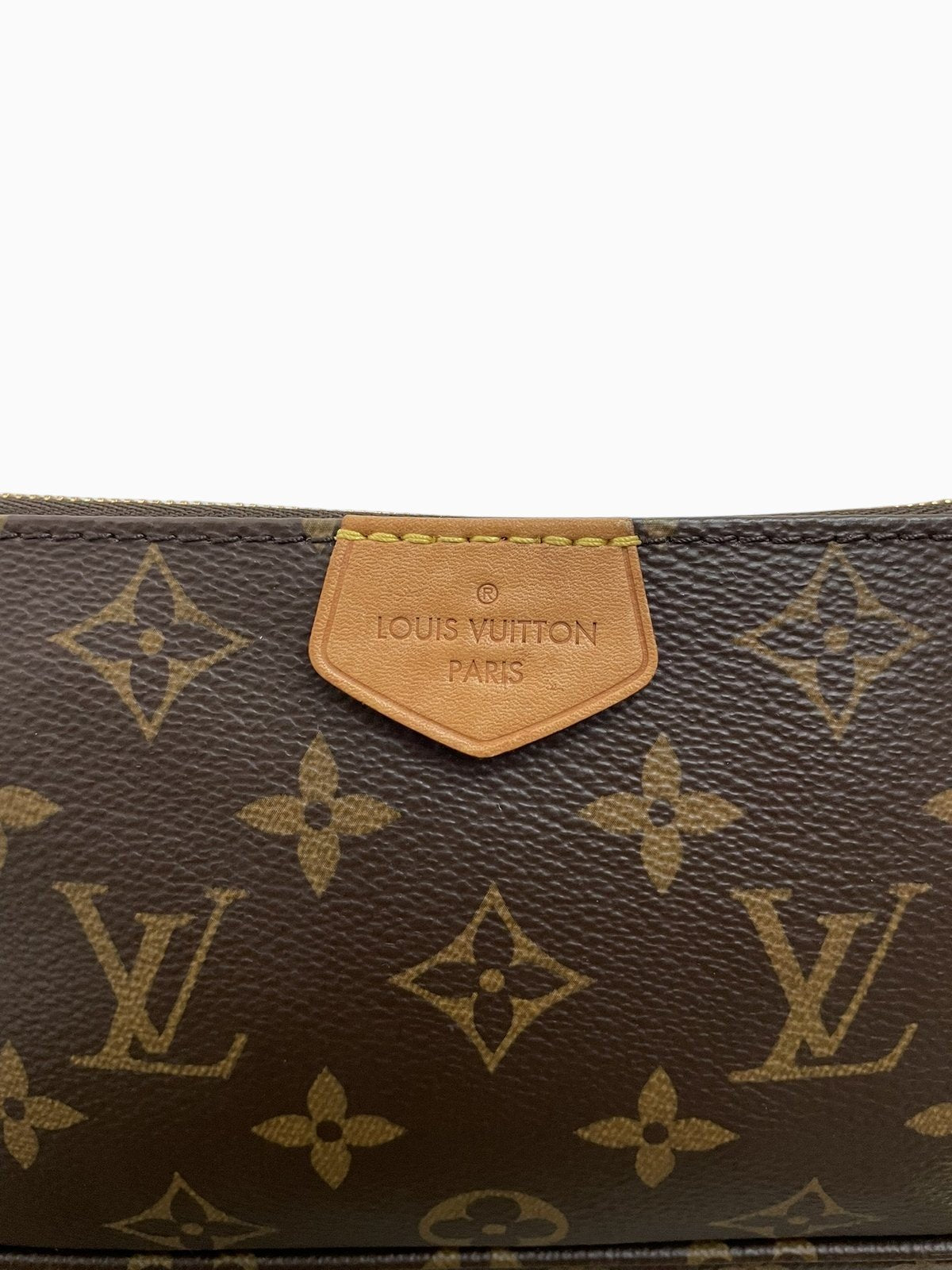 Dettaglio della linguetta in pelle vacchetta sulla pochette piccola Louis Vuitton