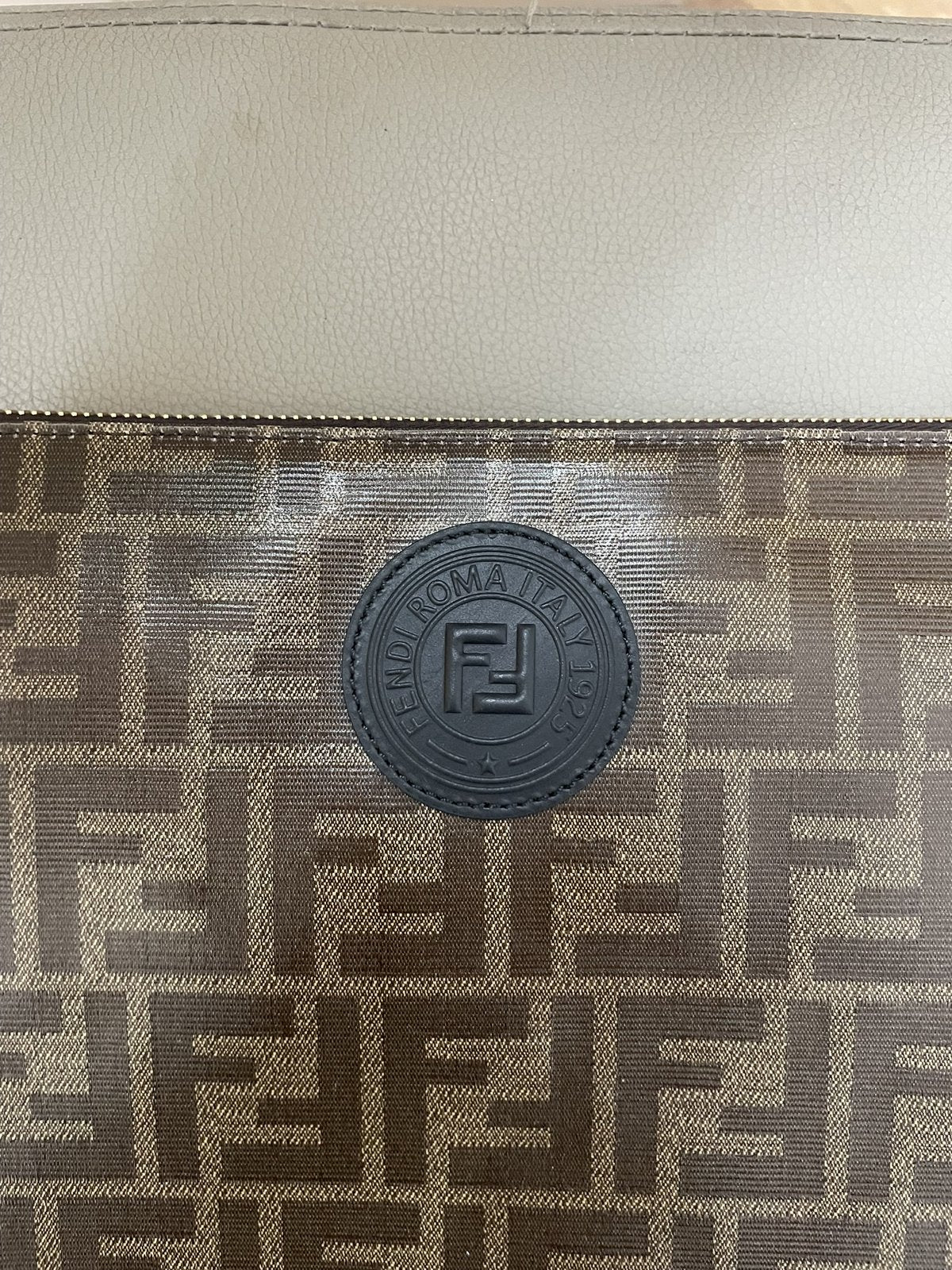 Dettaglio del patch circolare in pelle blu scuro con logo Fendi Roma Italia impresso sulla tela monogram FF