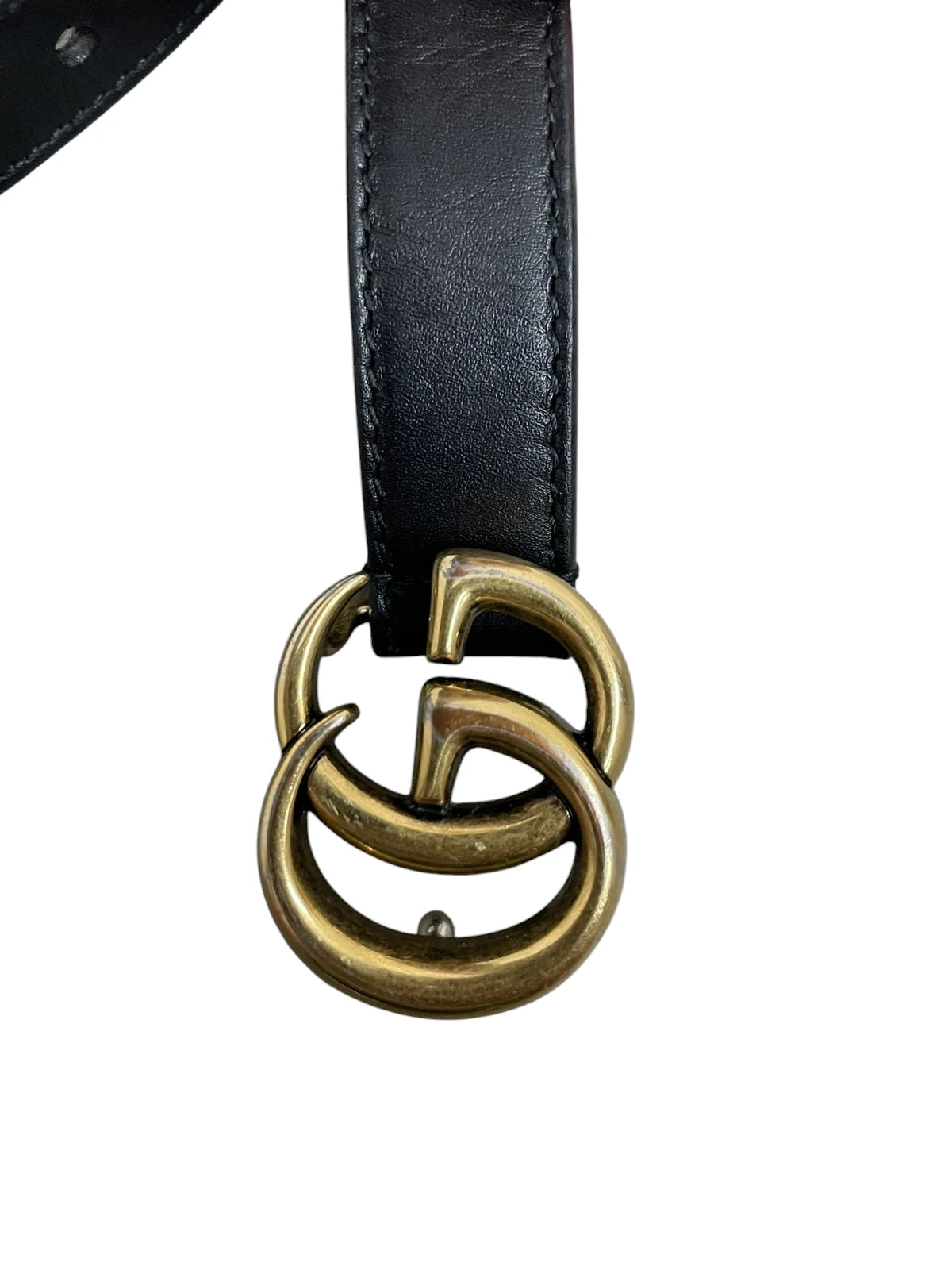 Dettaglio ravvicinato della fibbia Doppia G di Gucci in metallo color oro con finitura anticata.