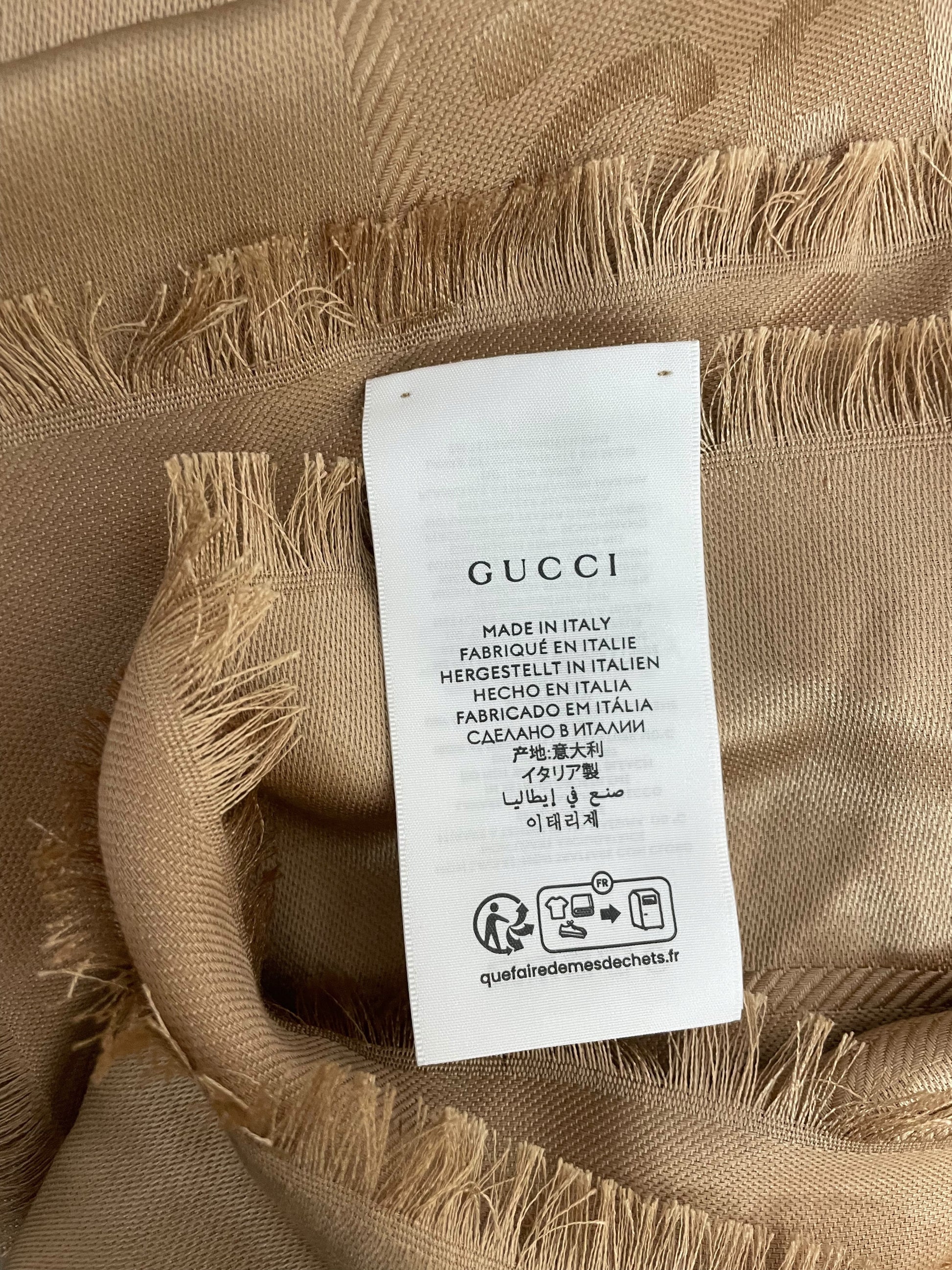 Etichetta Gucci Made in Italy su scialle cammello