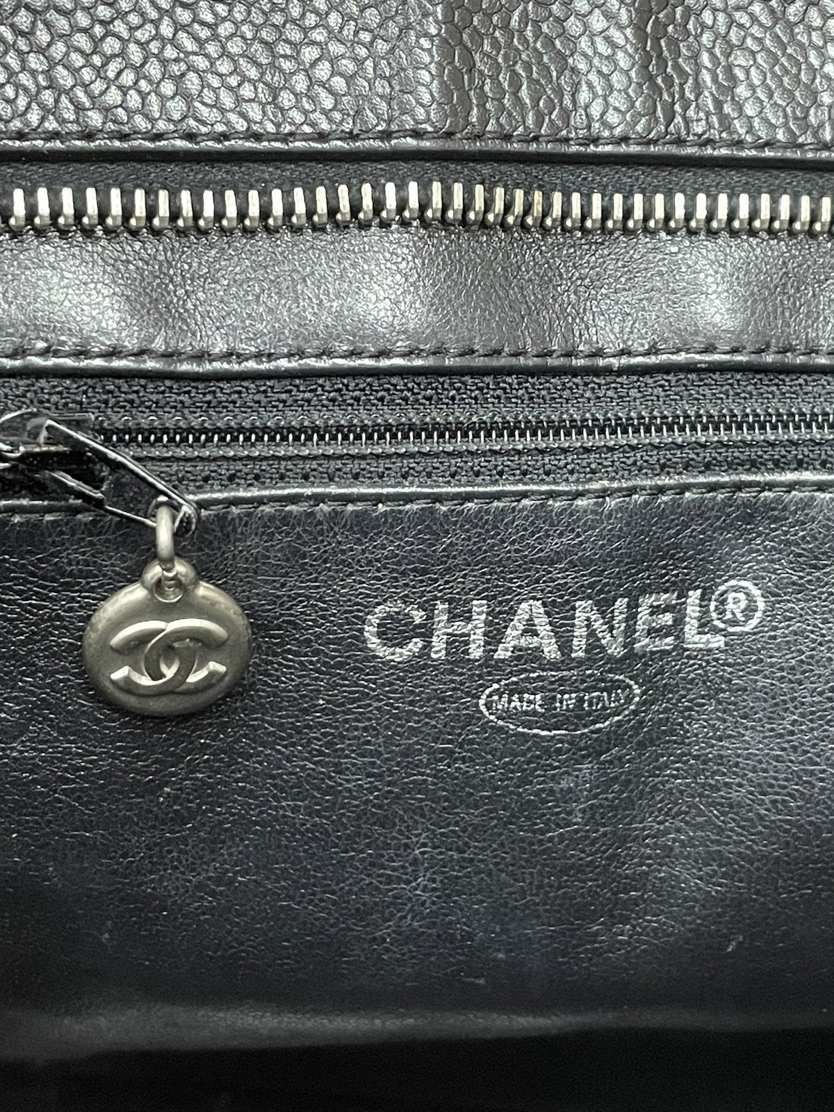 Dettaglio del logo Chanel stampato in lettere argentate all'interno e del piccolo medaglione tiralampo della tasca interna