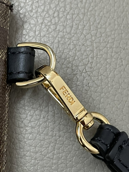 Particolare del moschettone in metallo dorato con incisione Fendi e cinturino da polso in pelle nera