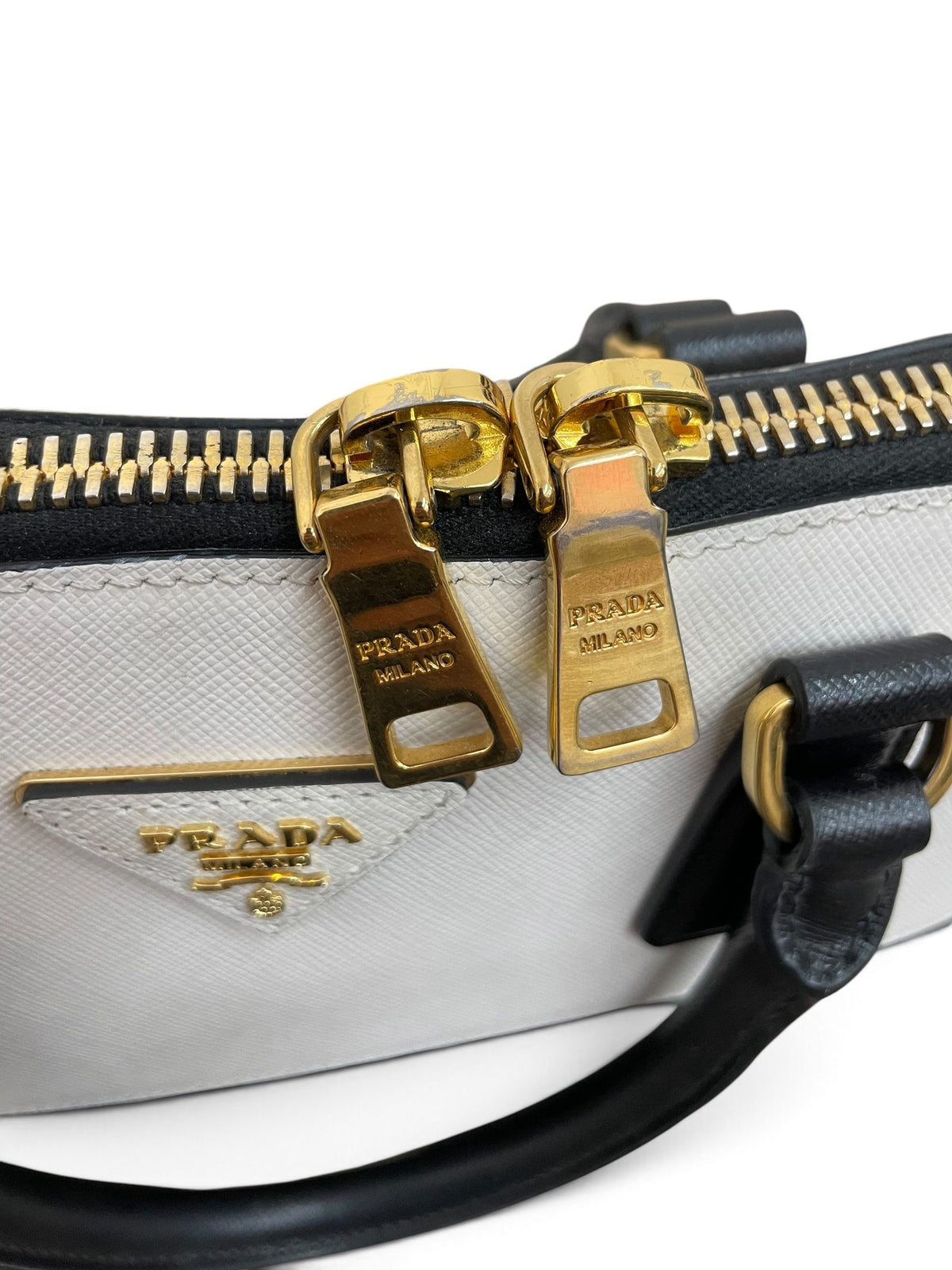 Dettaglio doppi cursori zip dorati e placca triangolare Prada Milano