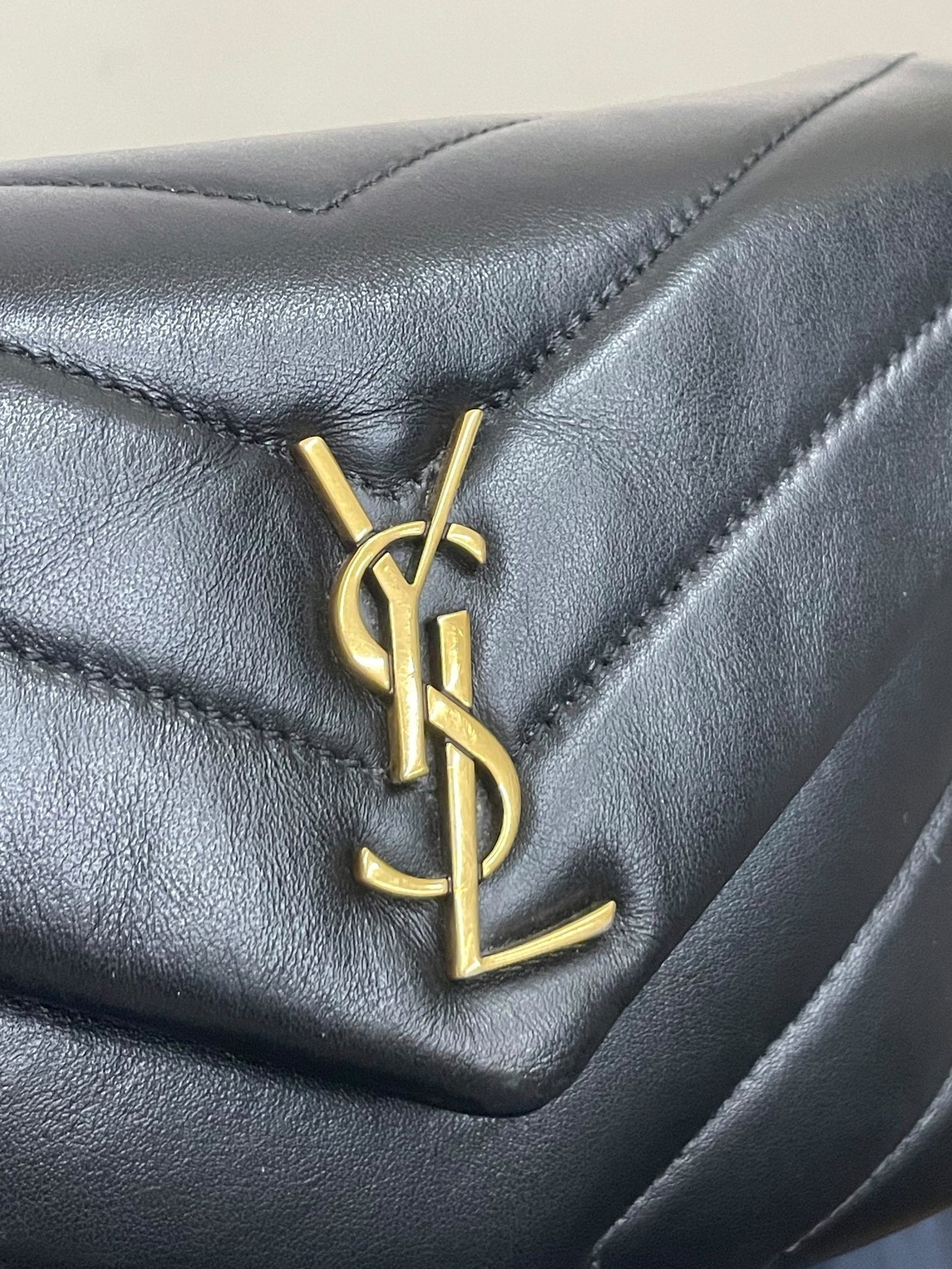 Dettaglio logo YSL dorato su pelle nera matelassé