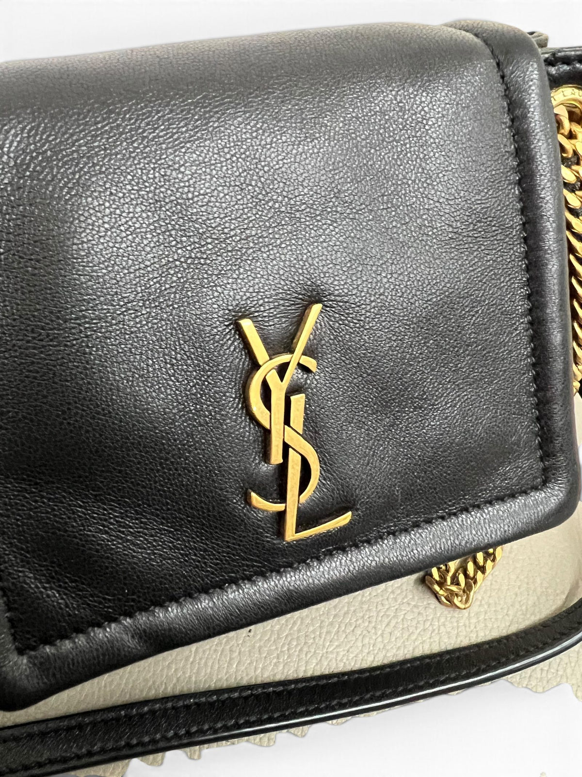 Dettaglio logo YSL dorato su borsa Saint Laurent nera